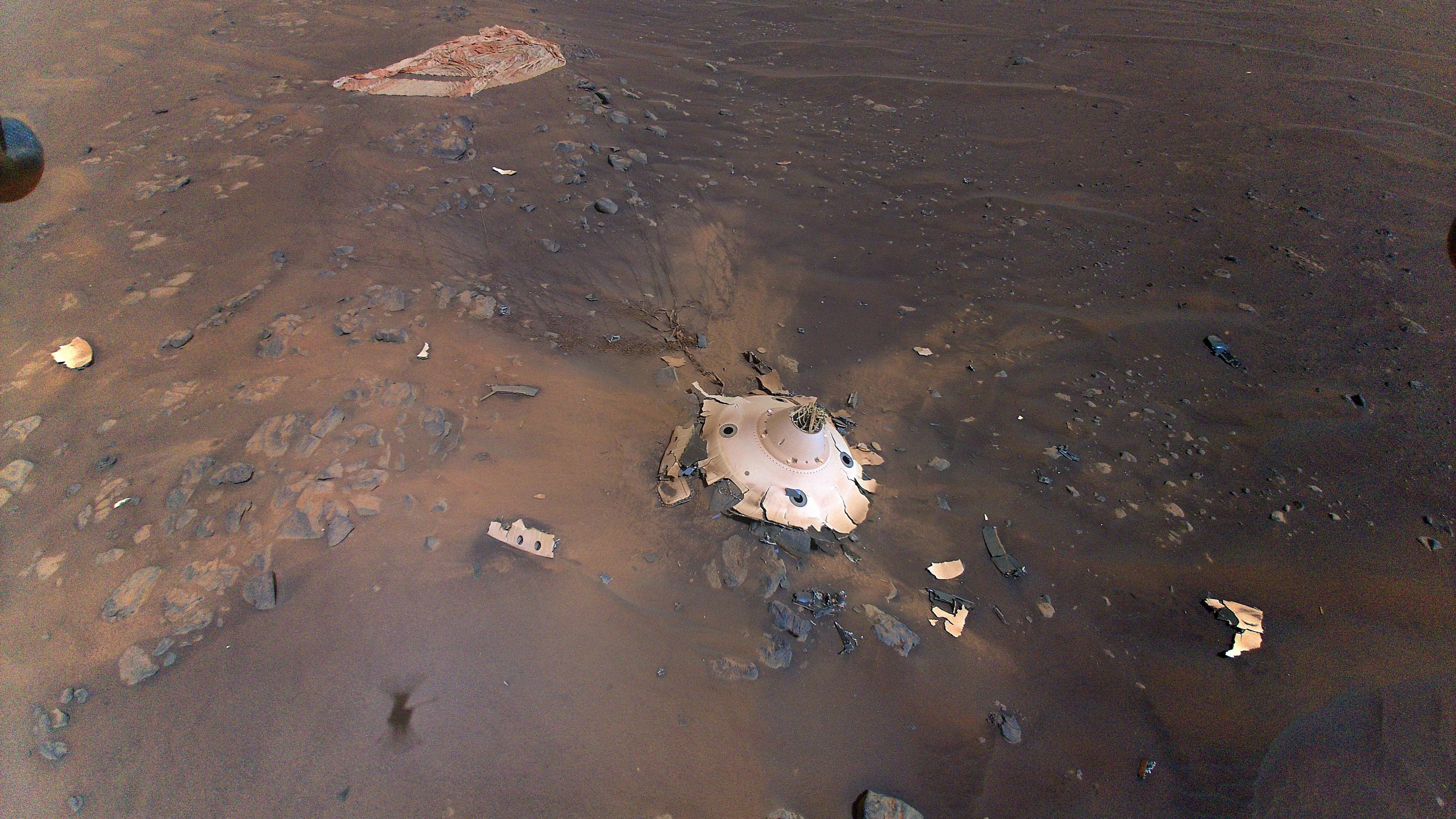 An aerial image of the Perseverance rover's backshell sitting upright on the surface of Jezero Crater, Mars.